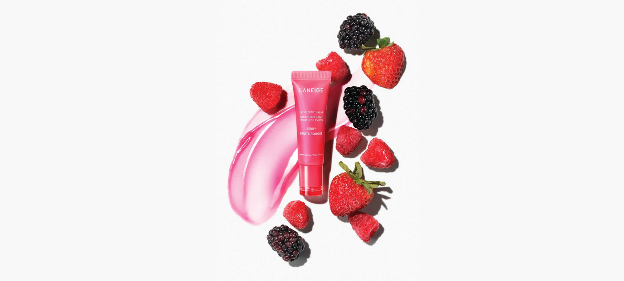 Pink skincare product with strawberries and blackberries on a white background